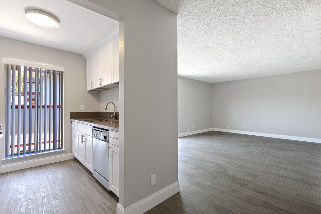 an empty kitchen and living room with wood flooring