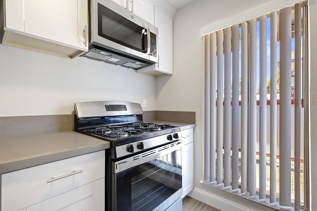 a kitchen with a stove and microwave and a window