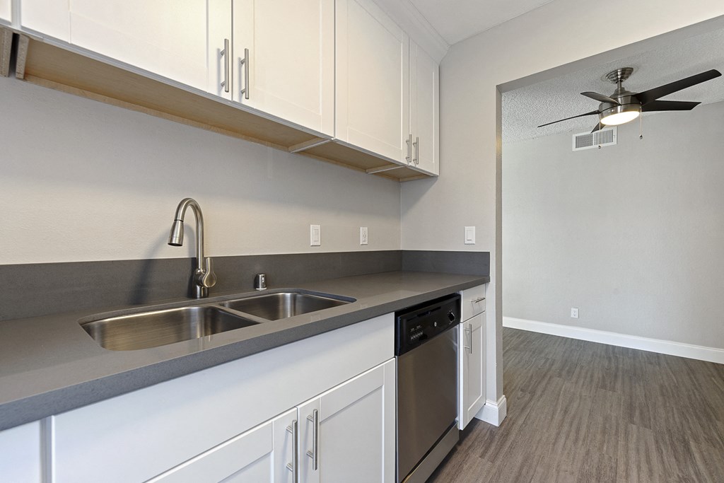 an empty kitchen with white cabinets and a stainless steel sink