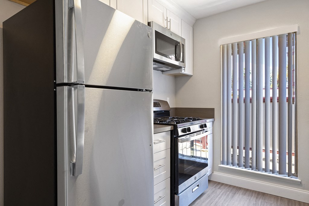 a kitchen with a refrigerator and stove and a window