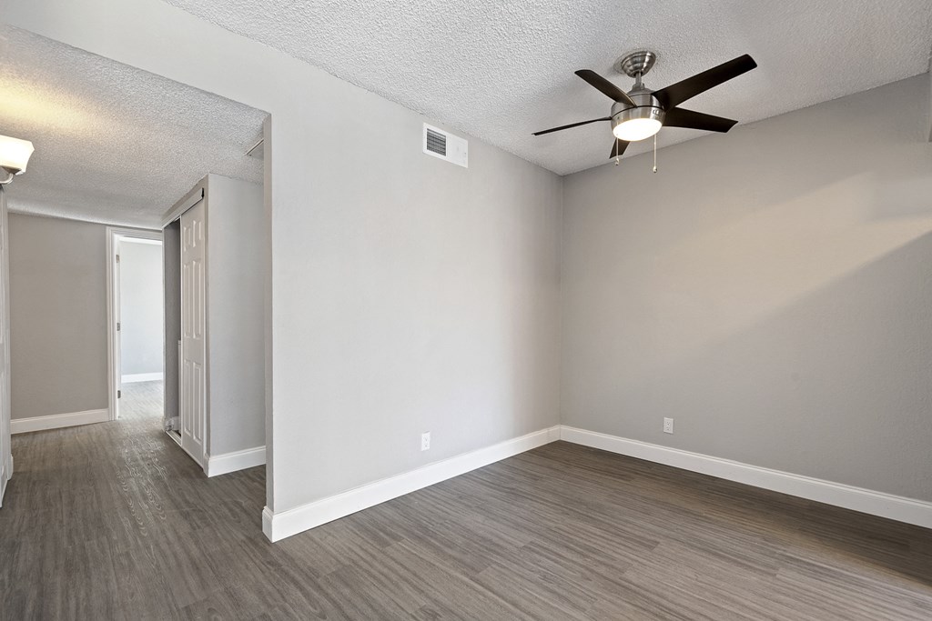 an empty living room with wood floors and a ceiling fan