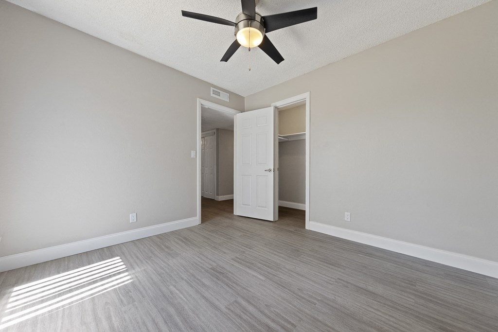an empty living room with a ceiling fan and a closet