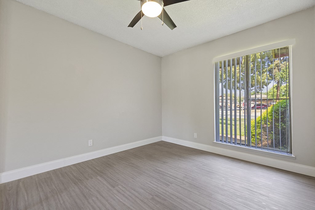 an empty living room with a large window and wood flooring