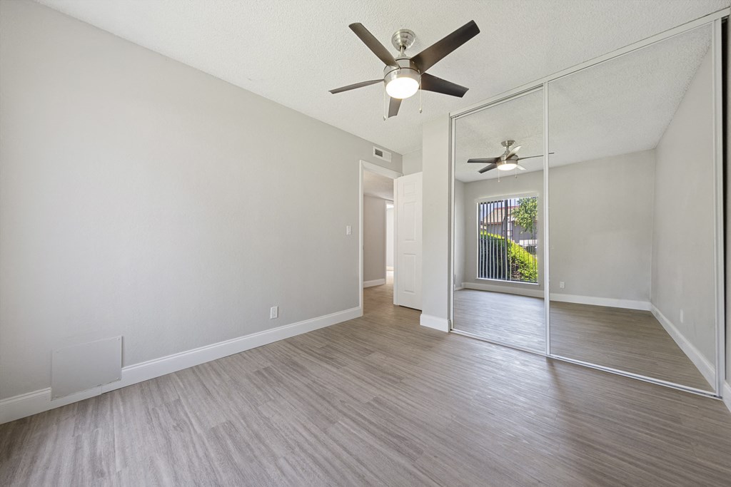 an empty living room with a ceiling fan and a mirror