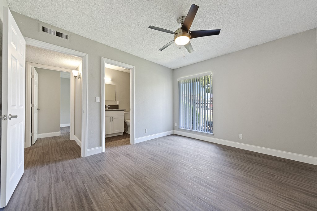 an empty living room with a ceiling fan and a window