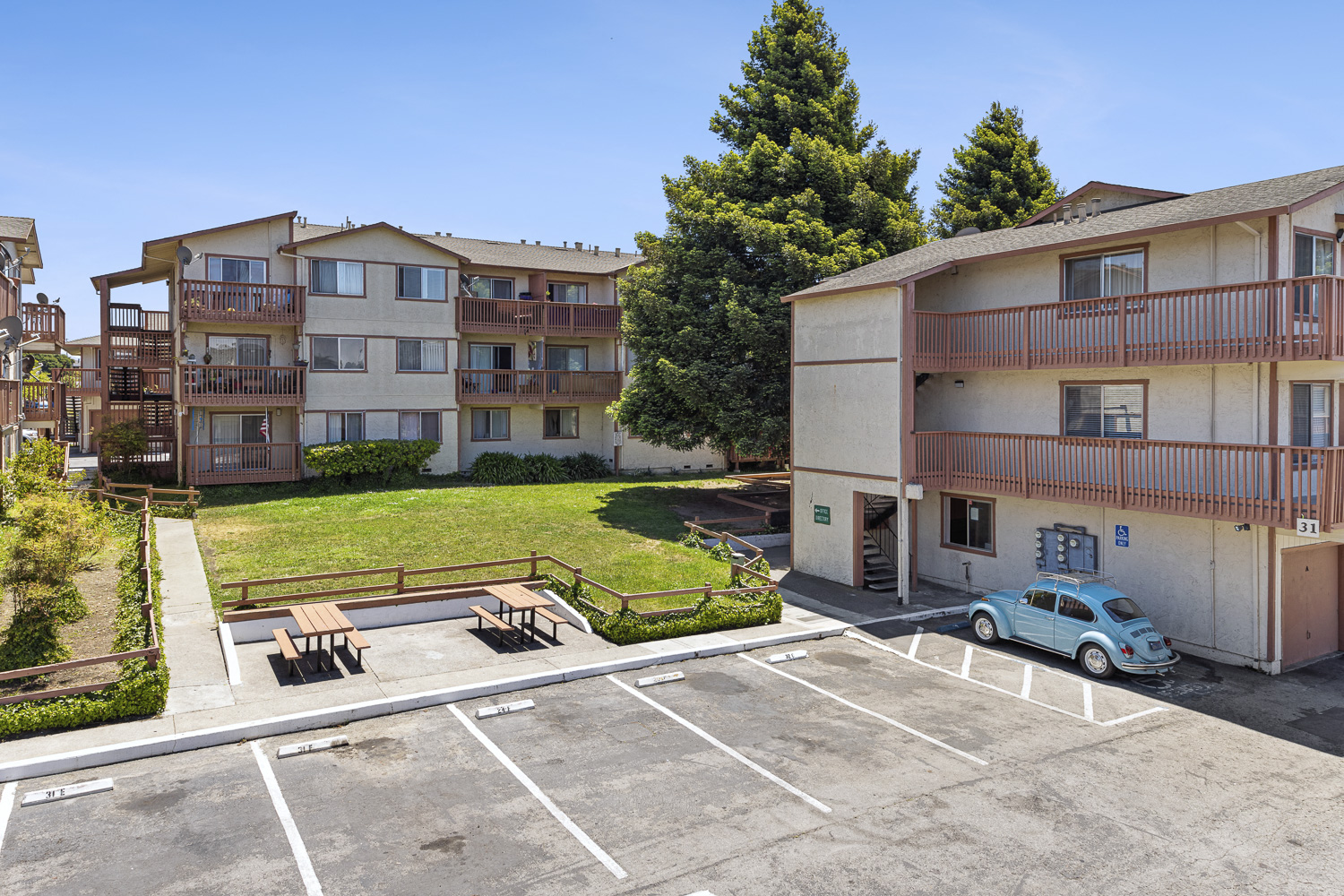 an empty parking lot in front of an apartment building with a blue car parked