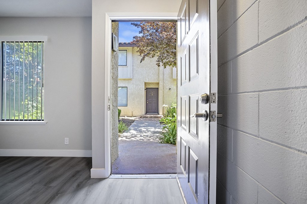 an open door leading to a courtyard with a building in the background