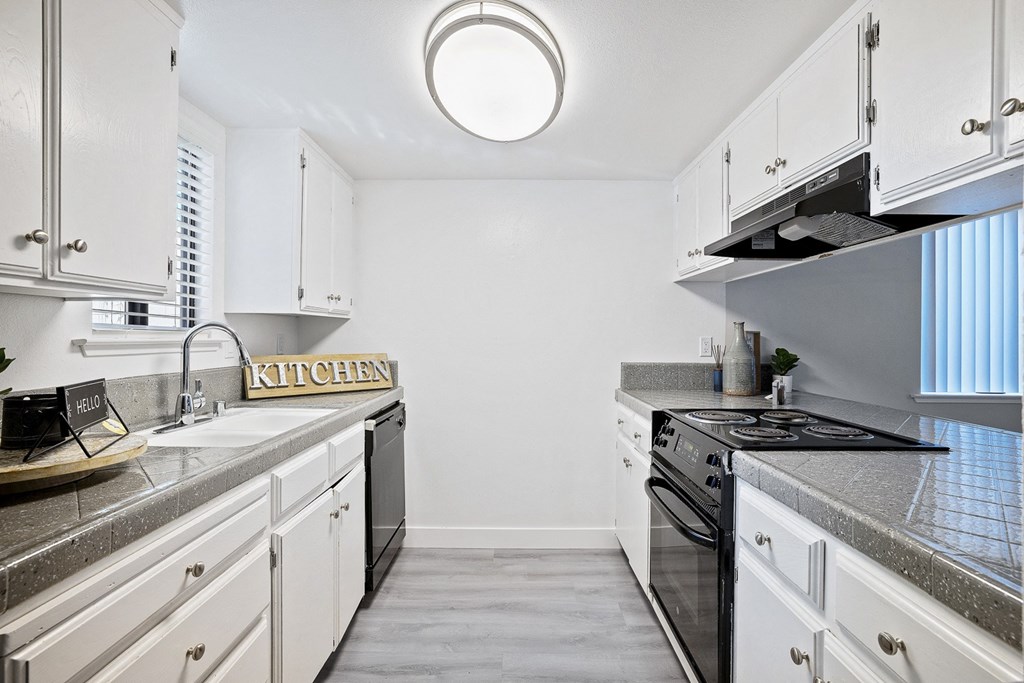 an empty kitchen with white cabinets and granite counter tops