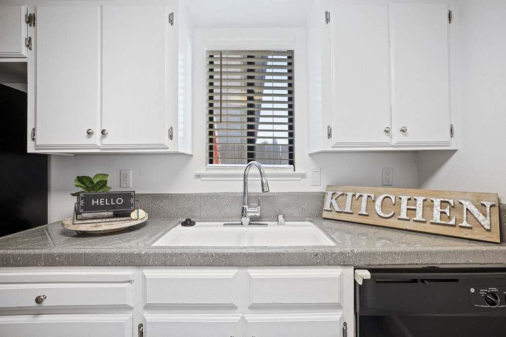 a kitchen with white cabinets and a sink and a window