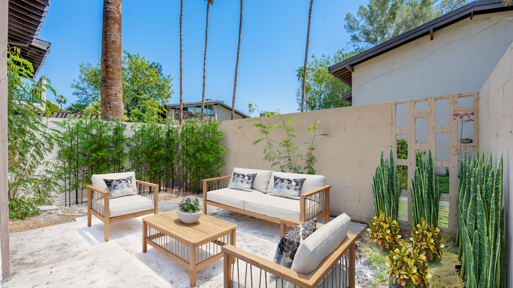 a patio with two couches and a coffee table in front of a concrete wall
