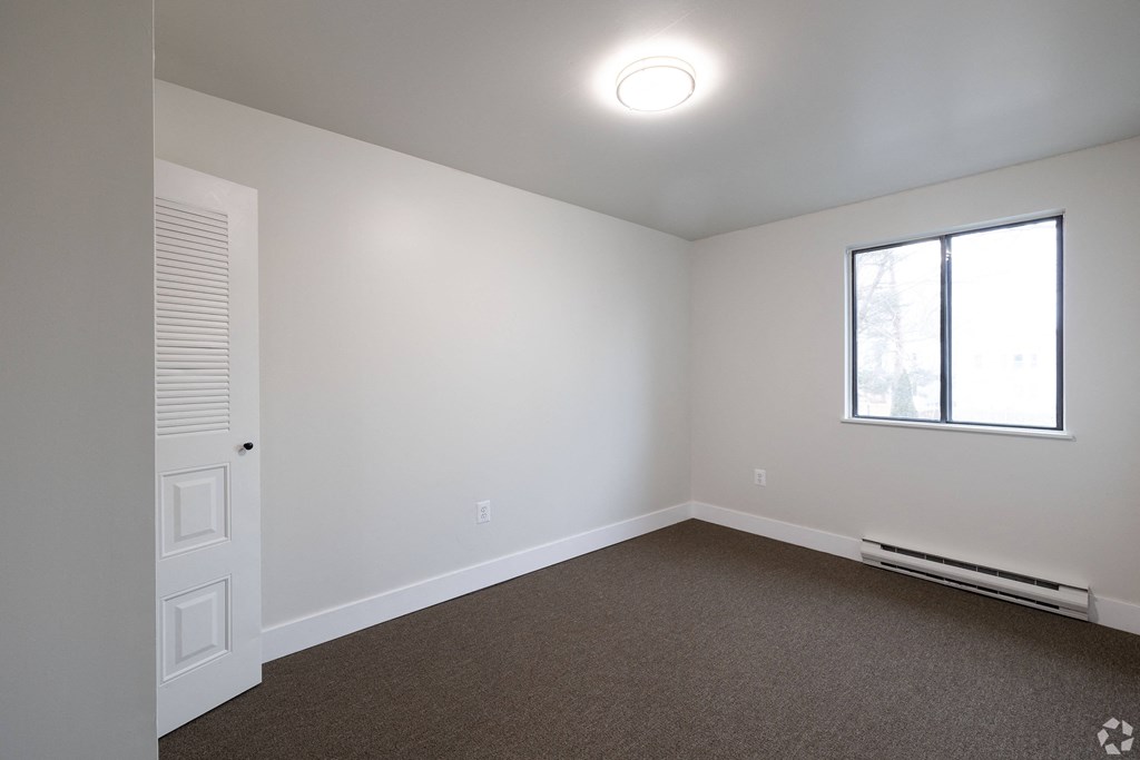 an empty room with white walls and a window