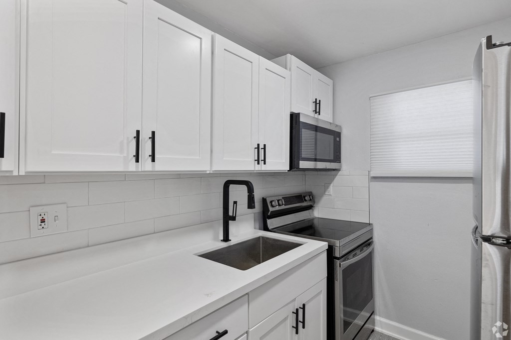 a kitchen with white cabinets and a sink and a refrigerator