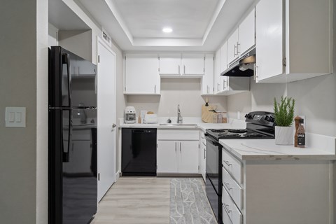 A modern kitchen with white cabinets and black appliances.