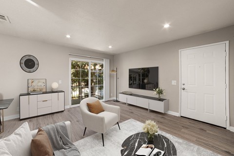 A living room with a white chair, a coffee table, and a flat screen TV.