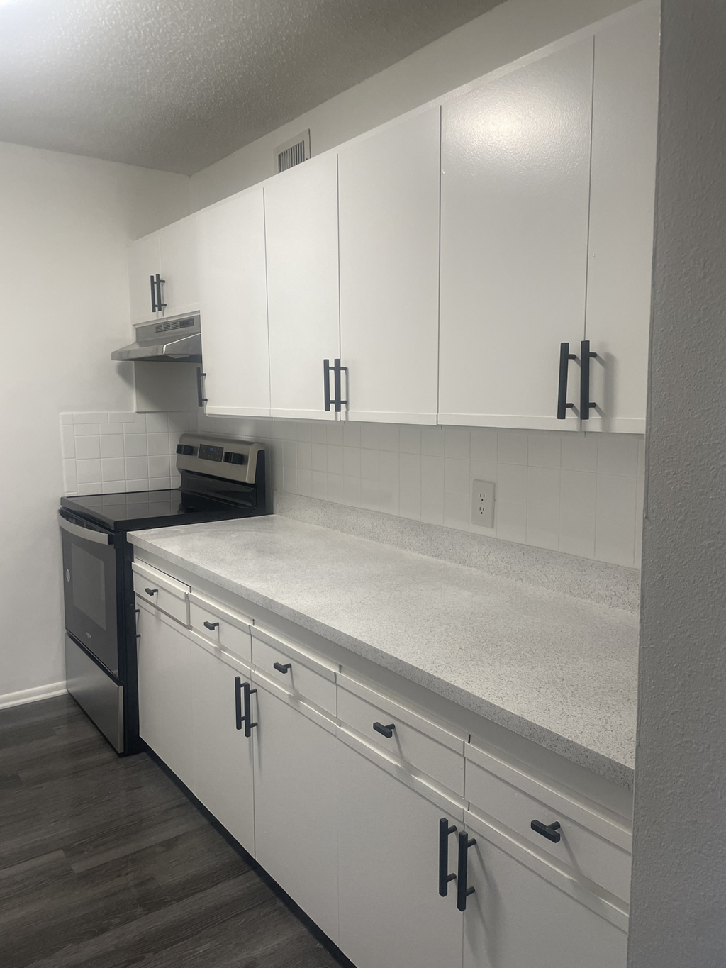 an empty kitchen with white cabinets and a black stove