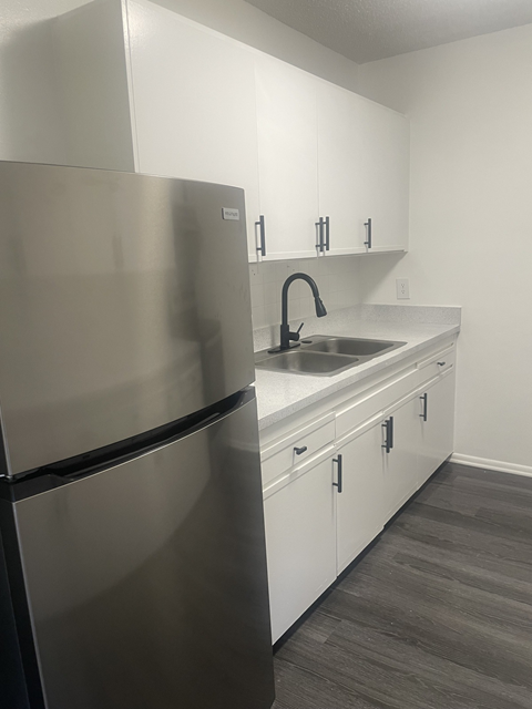 a kitchen with white cabinets and a stainless steel refrigerator and sink