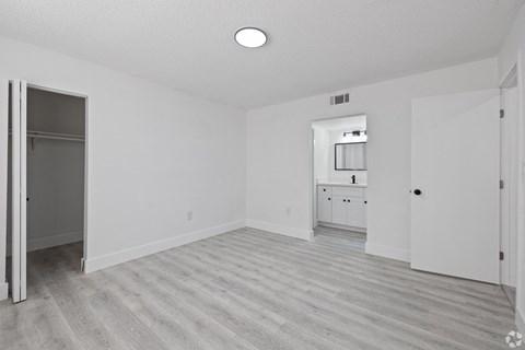 an empty living room and kitchen with white walls and wood flooring