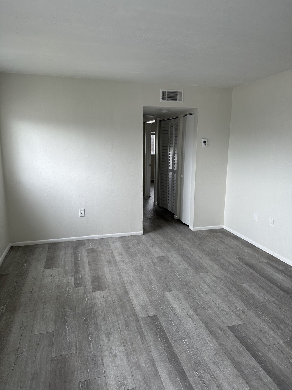 an empty living room with wood flooring and white walls