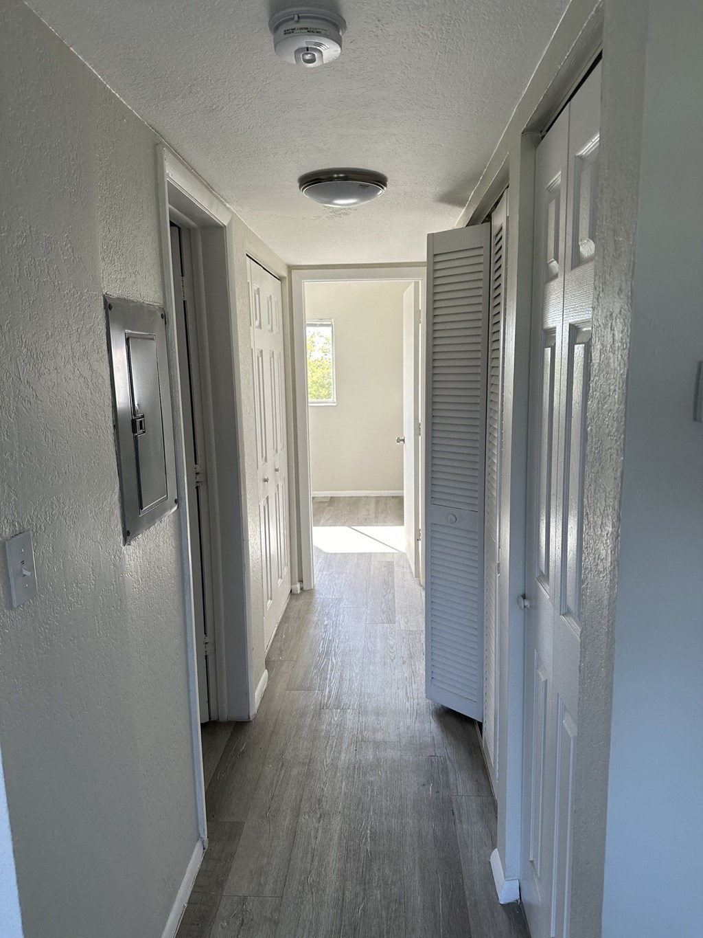 a hallway with white doors and white walls and a wood floor