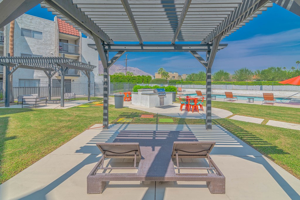 a patio with two picnic tables and two chairs under a shade