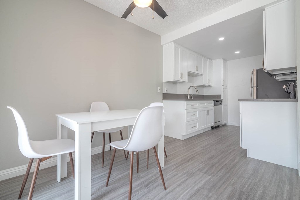 a dining room and kitchen with a white table and chairs