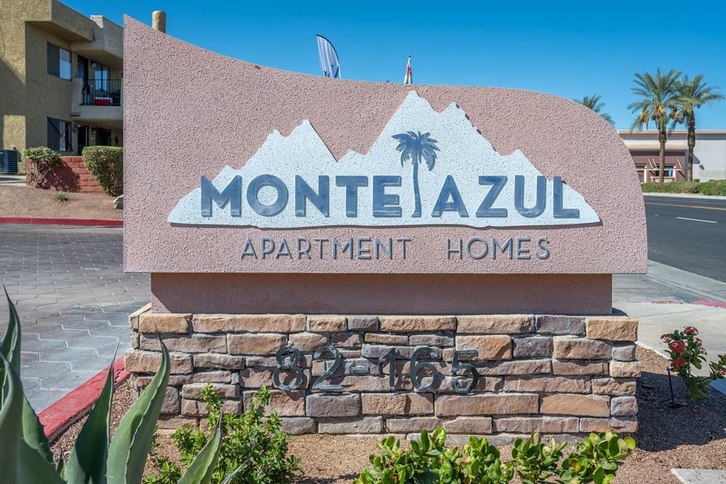 A sign for Montezul Apartment Homes with a mountain and palm tree graphic.