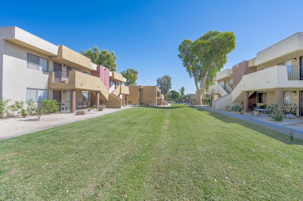 A row of apartment buildings with a green lawn in front.