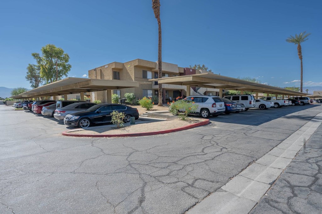 a parking lot in front of a hotel with cars parked