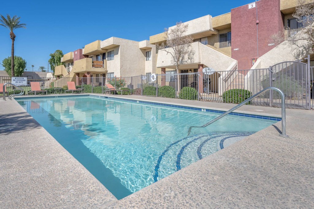A swimming pool in front of a building with a fence around it.