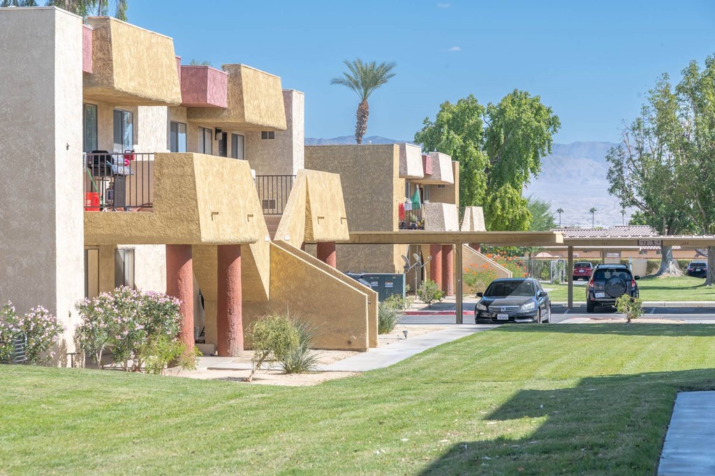 A building with a yellowish facade and a green lawn in front.