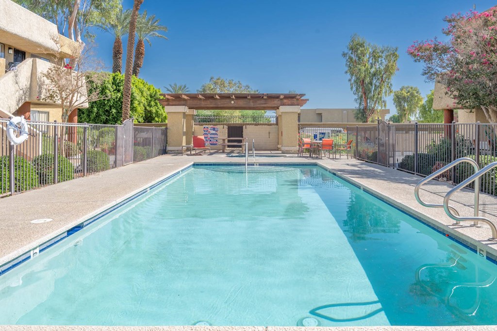 A swimming pool in a backyard with a fence around it.