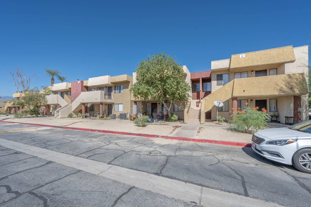 a row of apartment buildings on a street with a car parked