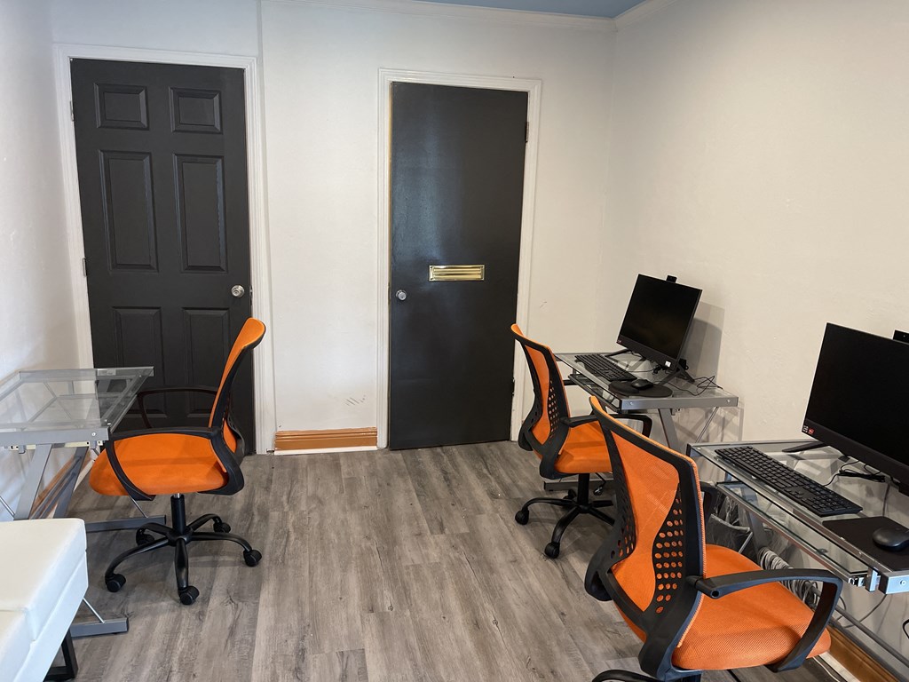 a room with two computers and two orange chairs