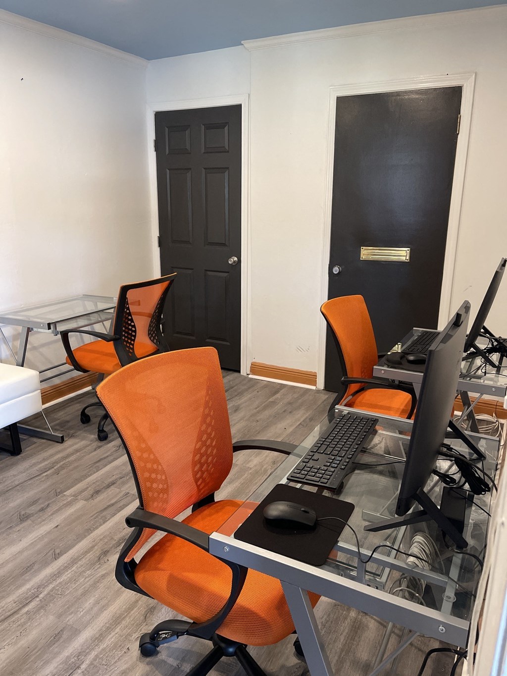 a room with two computer desks and two orange chairs