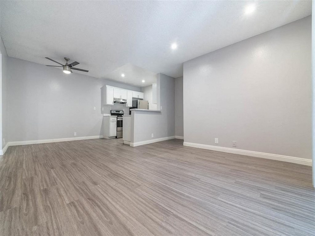 an empty living room with white walls and a ceiling fan