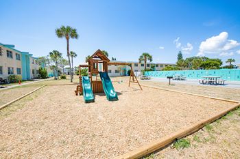 a playground with slides and a swing set in front of a swimming pool