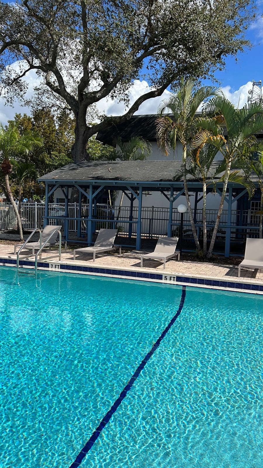 a swimming pool with chairs and a building in the background