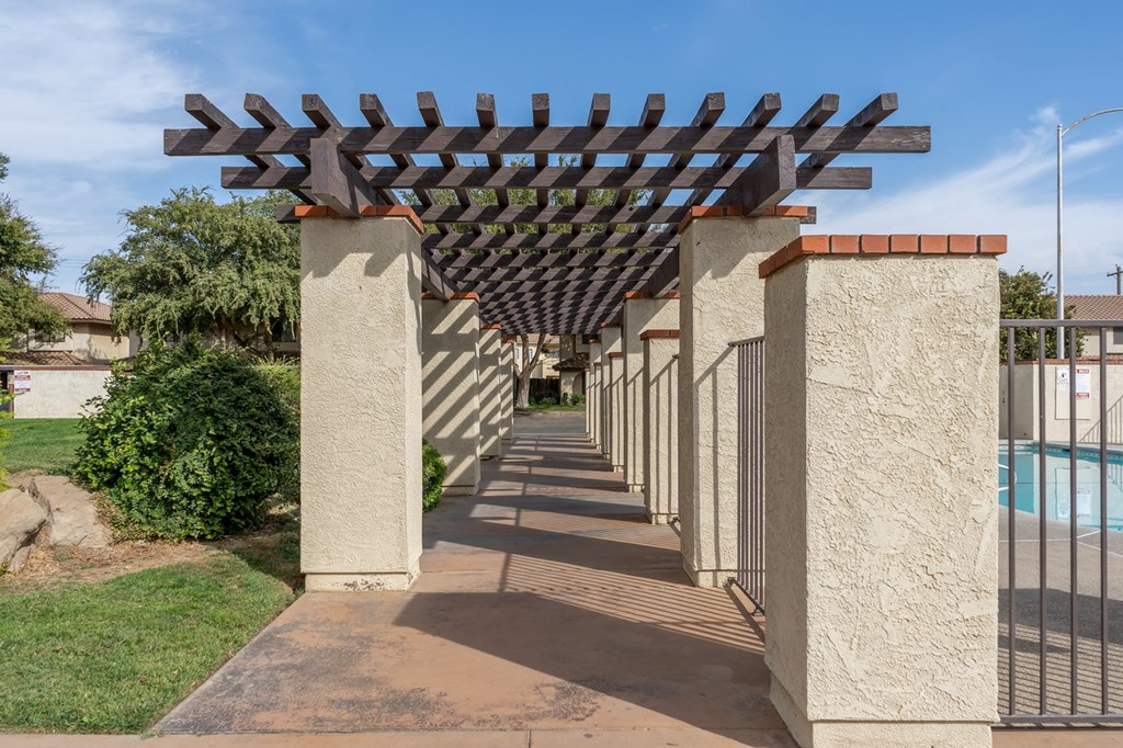 a row of pillars with awnings on a sidewalk near a pool