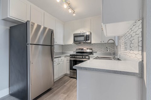 a kitchen with white cabinets and stainless steel appliances