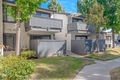 an exterior view of an apartment building with trees and a sidewalk