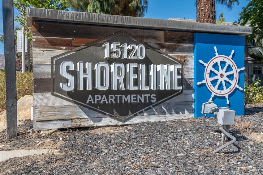 a sign for shoreline apartments in front of a building with a boat propeller