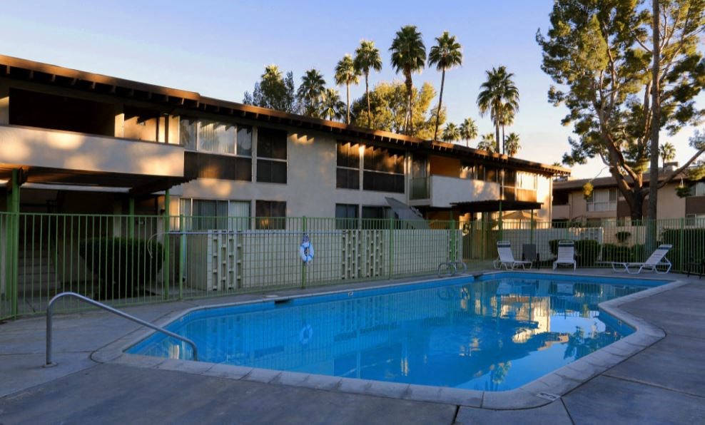 a swimming pool in front of a hotel with palm trees