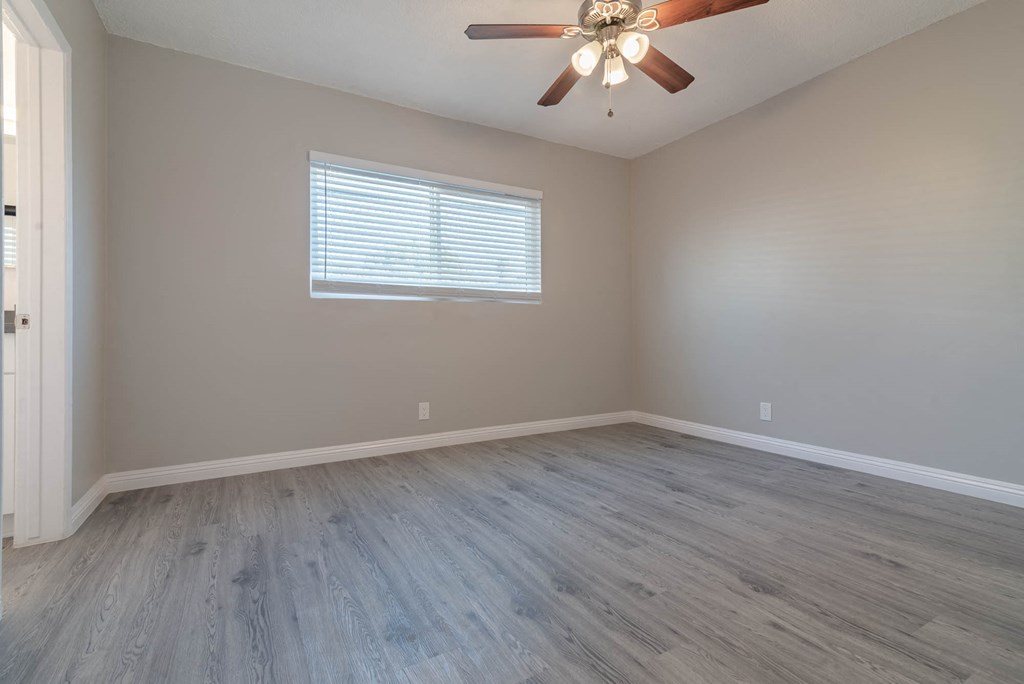 an empty bedroom with wood floors and a ceiling fan