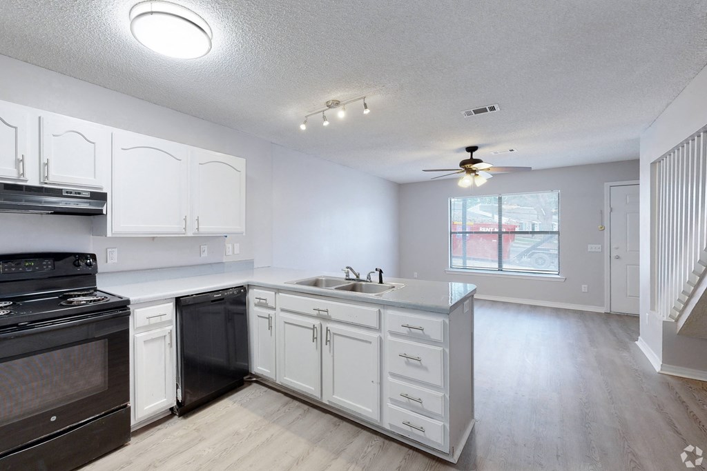 a kitchen with white cabinets and black appliances