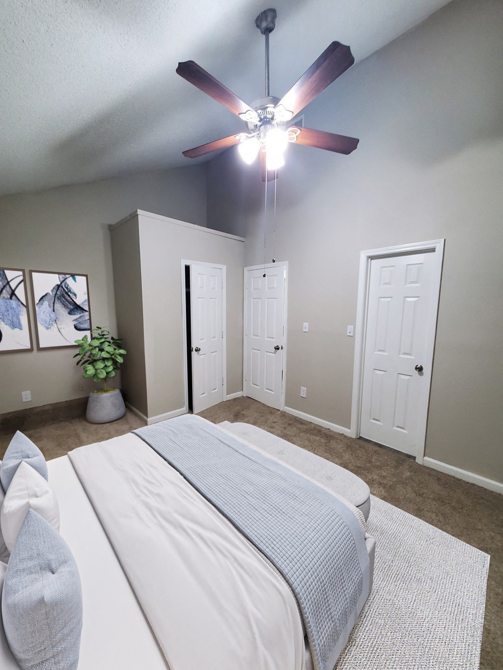 a bedroom with a large white bed and a ceiling fan