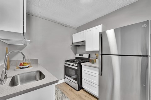 A modern kitchen with a stainless steel refrigerator, sink, and stove.