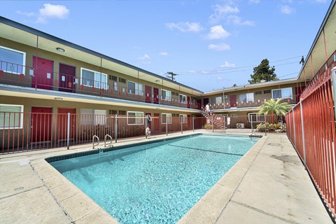 A swimming pool in front of a building with red doors.