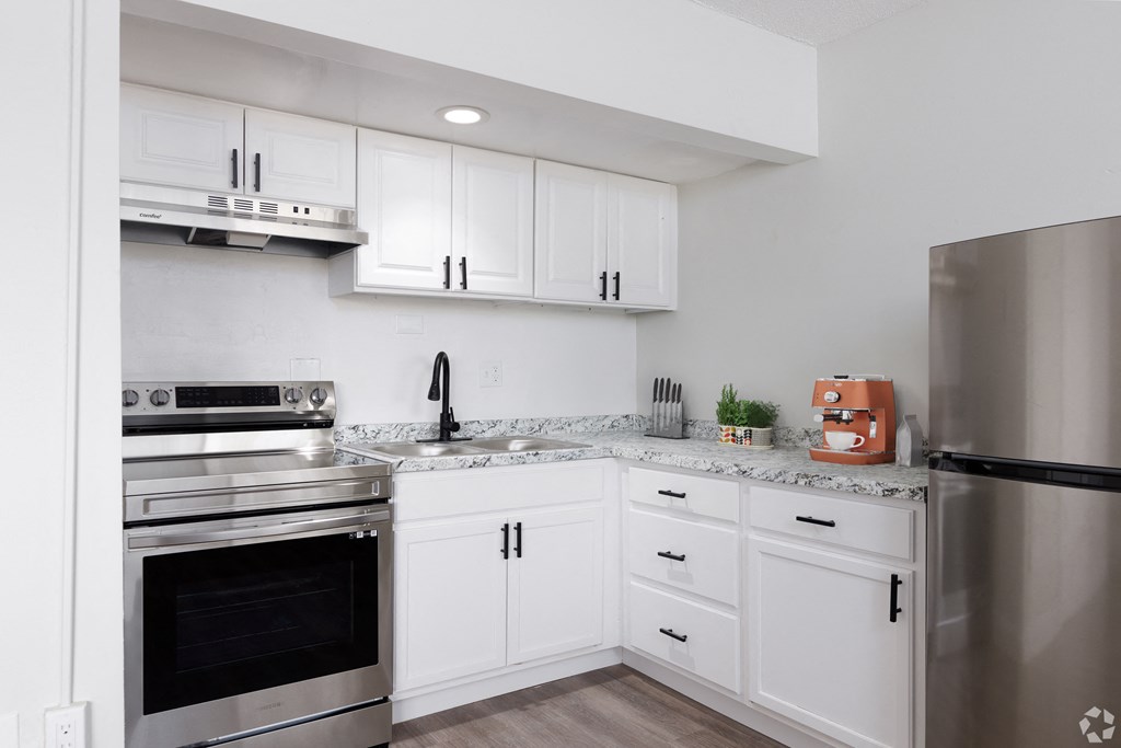 a kitchen with white cabinets and stainless steel appliances