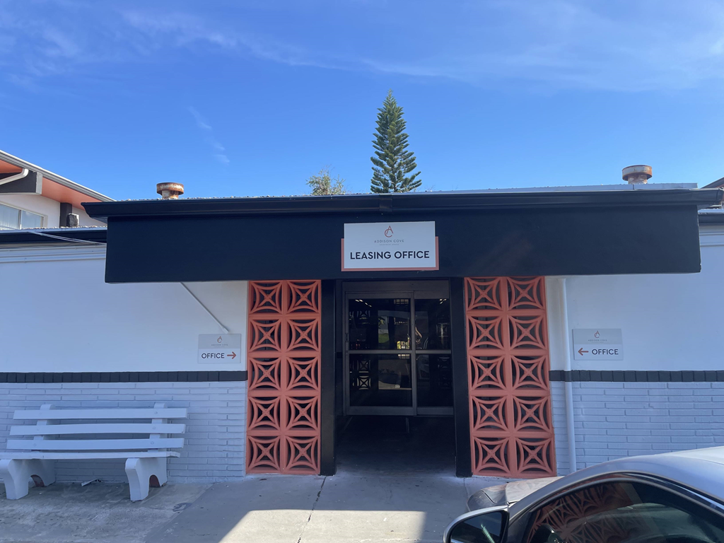a white building with a black awning and a bench in front of it