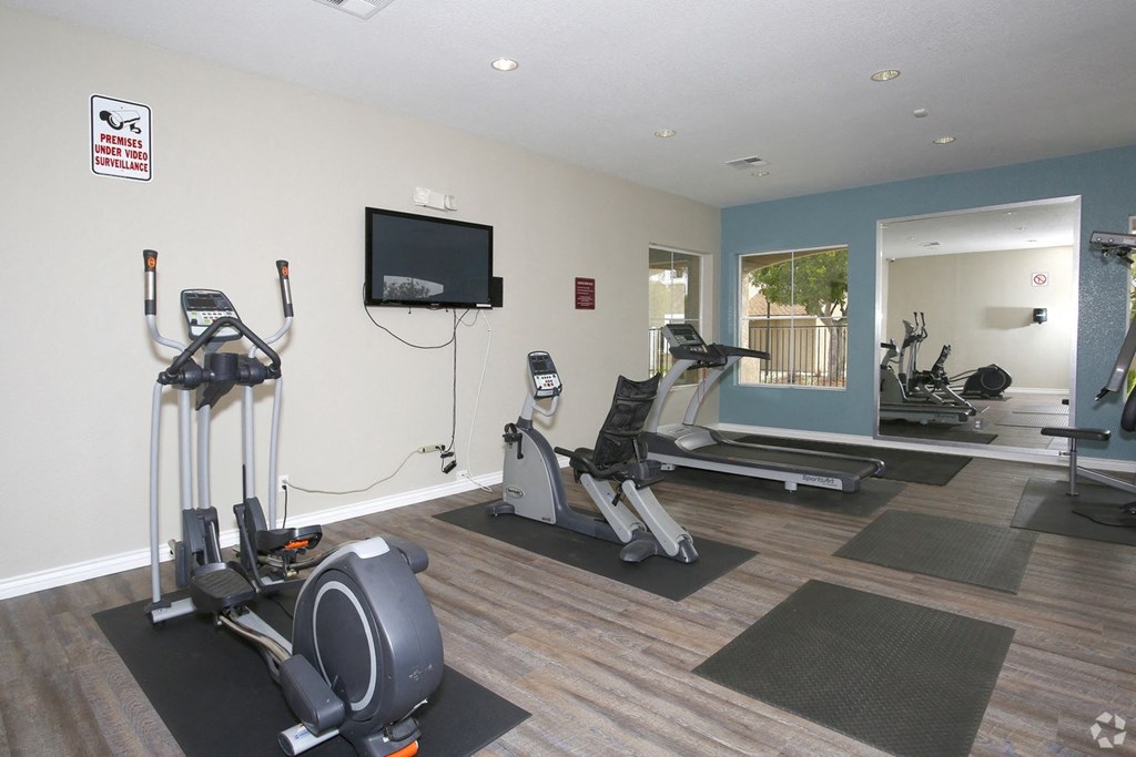 a gym with exercise equipment and a tv